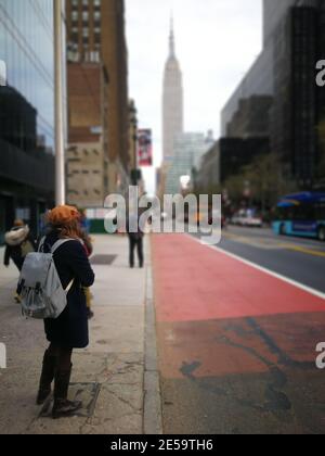 New York City, NY, USA - 04. November 2019. Eine Frau, die auf dem Bürgersteig in Downtown Manhattan auf den Bus wartet. Stockfoto