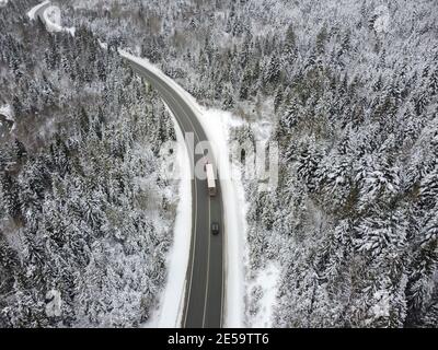 Kurvige Straße durch den Wald im Winter. Asphalt durch den Pass auf die Spitze des Berges in Rumänien Stockfoto