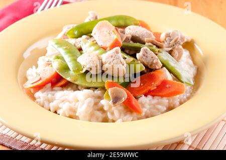 Huhn mit frischem Gemüse über cremigem Risotto Stockfoto