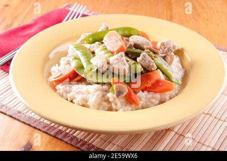 Huhn mit frischem Gemüse über cremigem Risotto Stockfoto