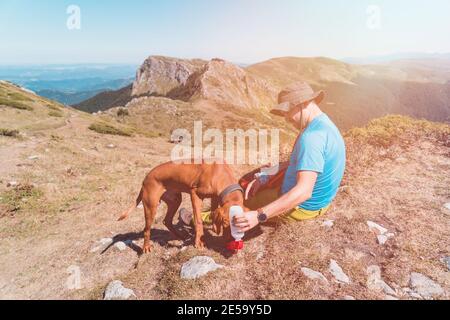 Abenteuerliche Mann Wanderer und Hund nehmen eine Pause an Die Spitze des Berges mit toller Aussicht Stockfoto