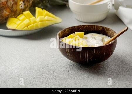 Gesundes Frühstückssaft, Joghurt mit frischer Mango und Ananas in der Kokosnussschale Stockfoto
