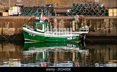 FINDOCHTY MORAY KÜSTE SCHOTTLAND FISHERMENS CREELS ODER HUMMERTÖPFE UND EIN GRÜNES FISCHERBOOT IM HAFEN Stockfoto