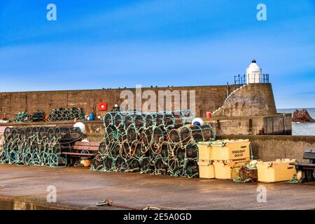 FINDOCHTY MORAY COAST SCOTLAND FISHERMENS CREELS ODER HUMMERTÖPFE ORDENTLICH GEGEN DIE HAFENMAUER GELAGERT Stockfoto