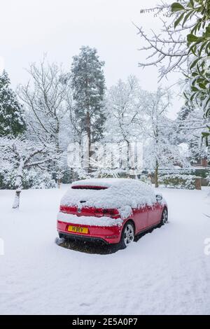 Ein rotes Volkswagen Golf GTI-Auto, das während eines starken Schneefalls im Winter in einer Vorstadtfahrt geparkt wurde: Woking, Surrey, Südostengland Stockfoto