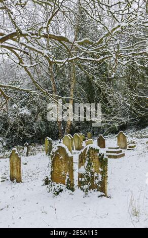 Friedhof und Grabsteine in St. John's Church bei Woking, Diözese Guildford, Surrey, Südostengland nach einem starken Schneefall im Winter Stockfoto