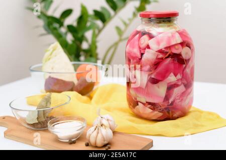 Eingelegter rosafarbener Kohl fermentativ mit Rüben und Karotten in Salzlake In einem Glas auf einem hellen Hintergrund Stockfoto