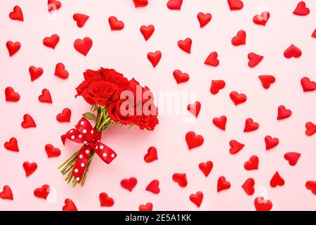 Valentinstag-Konzept. Roter Rosenstrauß und rote Herzen auf rosa Hintergrund. Flach liegend Stockfoto