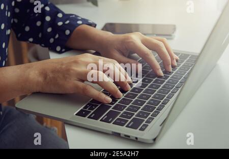 Die Hand der Frau mit einer Tastatur auf einem Laptop-Computer. Geschäftskonzept. Arbeiten Sie von zu Hause aus. Stockfoto