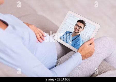 Schwangere Frau macht Videoanruf mit ihrem Arzt auf digital Tablet Stockfoto