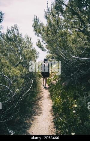 Ein Mädchen auf dem Rücken, das einen Fußweg hinuntergeht Wilde Vegetation Stockfoto
