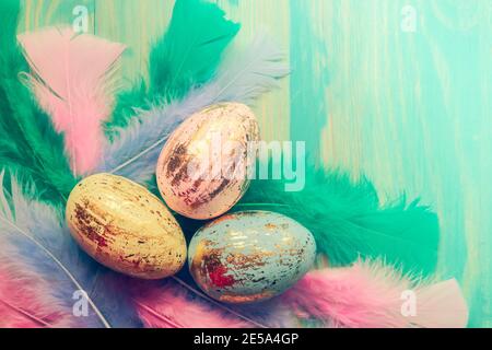Osterhintergrund mit bunten oder Pastellfarben Ostereier und Federn auf Holztisch. Draufsicht. Flach liegend. Speicherplatz kopieren. Moderner Stil. Osterdekor Stockfoto