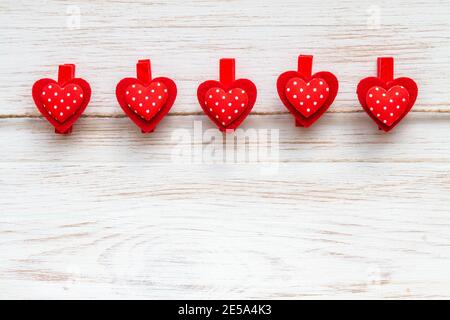 Rote Herzreihe mit Tupfen auf Wäscheklammern auf rustikalem Holzrand. Valentinstag Hintergrund mit Reihe von roten Herzen. Für Text platzieren Stockfoto