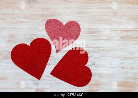 Valentinstag Komposition von glänzenden roten und rosa Papier geformten Herzen auf vintage weiß bemalten Hintergrund. Modell für Valentinstag mit Kopierplatz. Stockfoto