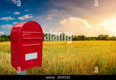 Große rote gemütliche Briefkasten mit weißen leeren Notiz Platz für Adresse steht im Freien vor einer schönen Landschaft Bei Sonnenuntergang Hintergrund mit Stockfoto