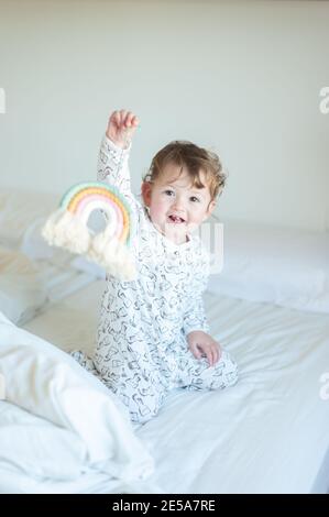 Kleines Mädchen trägt Schlafanzug spielen im Bett Stockfoto