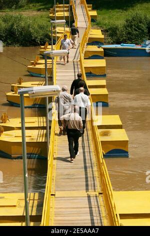 Menschen, die in Rumänien eine Fußgängerbrücke über einen Fluss überqueren Stockfoto