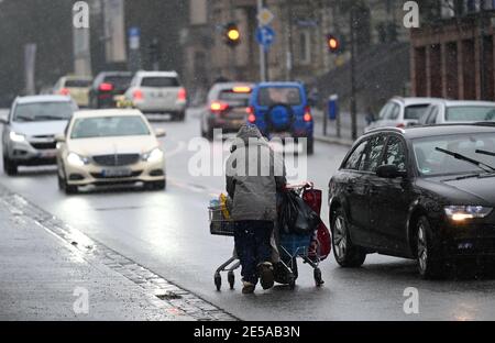 27. Januar 2021, Hessen, Frankfurt/Main: Autos weichen einer Obdachlosen aus, die ihre Habseligkeiten in einen Einkaufswagen auf einer Straße in der Innenstadt schiebt. Foto: Arne Dedert/dpa Stockfoto