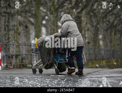 27. Januar 2021, Hessen, Frankfurt/Main: Eine obdachlose Frau schiebt ihr Hab und gut in einem Einkaufswagen entlang eines Weges am Mainufer. Foto: Arne Dedert/dpa Stockfoto