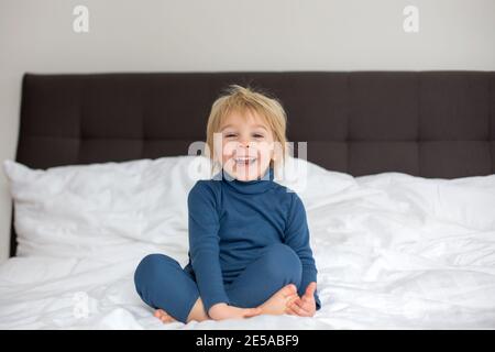 Cute blonde Kleinkind Kind, Saugen seinen Fuß Daumen, macht lustige Gesichter, lachen Stockfoto