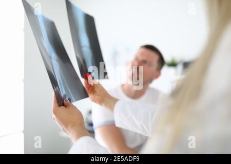 Arzt, der dem Patienten in der klinischen Nahaufnahme Röntgenaufnahmen zeigt Stockfoto