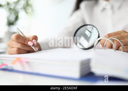 Weibliche Hände halten Lupe über Ordner mit Dokumenten Konzept Stockfoto