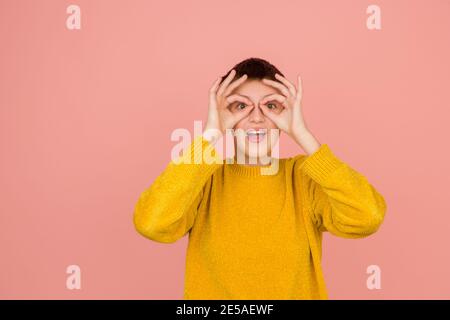 Superhelden-Brille. Kaukasische Mädchen Porträt auf Koralle rosa Studio-Hintergrund mit Copyspace für Anzeige. Schönes Modell in Pullover. Konzept der menschlichen Emotionen, Gesichtsausdruck, Verkauf, Werbung, Mode. Stockfoto