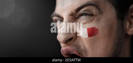 Ein schreiender Mann mit dem Bild des Maltas Flagge auf seinem Gesicht Stockfoto