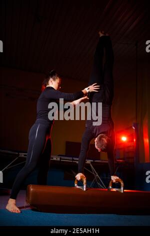 Ein Duo von Akrobaten, die einen Doppeltrick ausführen. Eine Frau im Turnanzug und ein Mann in Sportkleidung. Sehr flexible Zirkusartisten. Stockfoto