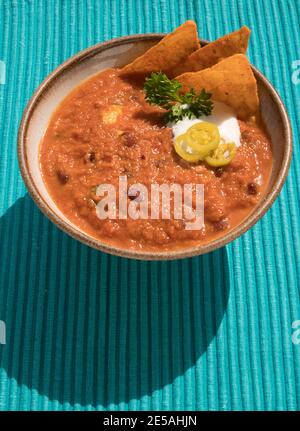 HAUSGEMACHTE VEGETARISCHE CHILI MIT MAIS NACHO CHIPS, SAURE SAHNE. PETERSILIE UND JALAPENO PFEFFER Stockfoto