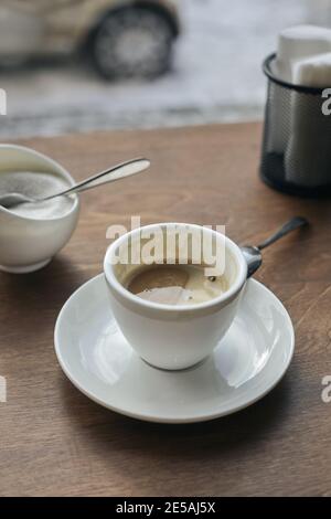 Die Hälfte trank Kaffee in einem weißen Kaffeebecher auf dem Tisch. Stockfoto