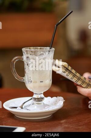 Halb trank Kaffee in einem transparenten Kaffeebecher auf dem Tisch. Stockfoto
