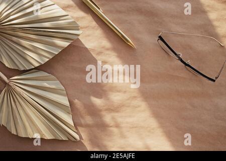 Minimale Standzeit für Schreibwaren. Trockene Palmblätter auf Bastelpapier. Stockfoto
