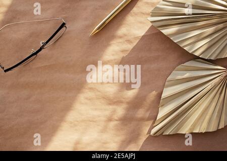 Minimale Standzeit für Schreibwaren. Trockene Palmblätter auf Bastelpapier. Stockfoto