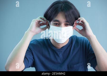 Nahaufnahme von jungen Mann in sterilen Gesichtsmaske isoliert Hintergrund. Epidemische Pandemie Coronavirus 2019, covid-19 Grippevirus-Konzept. Stockfoto