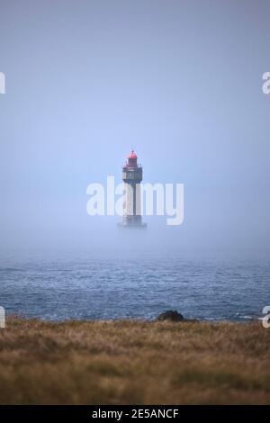 Der dramatische Leuchtturm La Jument, im Sommernebel geschrumpft, vor der Küste der Ile d'Ouessant in der Bretagne. Der ikonische 47 Meter hohe Leuchtturm war bui Stockfoto