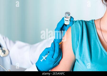 Frau Arzt oder Krankenschwester in Uniform und Handschuhe tragen Gesichtsmaske Schutz im Labor, Herstellung einer Injektion hält Impfstoffflasche mit COVID-19 Coronovirus V Stockfoto