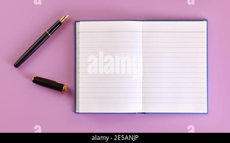 Draufsicht - schwarzer Füllfederhalter mit Goldspitze, geöffneter Kappe, leeres weißes Papierkissen auf fliederndem Brett in der Nähe Stockfoto