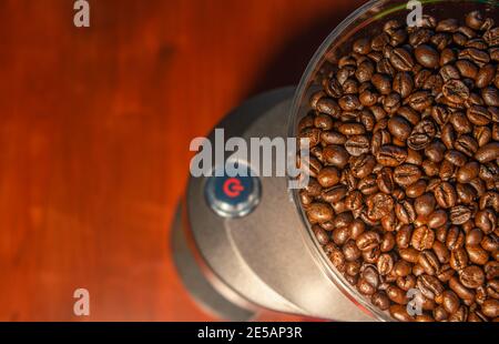 Kaffeemühle mit roter Starttaste, gefüllt mit frischen Kaffeebohnen und Kopierfläche im Hintergrund für Text Stockfoto