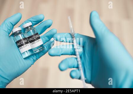 Arzt Hände in Schutzhandschuhen halten Vacive und Spritze Stockfoto