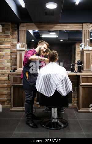 Fröhlicher junger, gutaussehender Mann, der im friseursalon einen Friseurbesuch abstattet Stockfoto