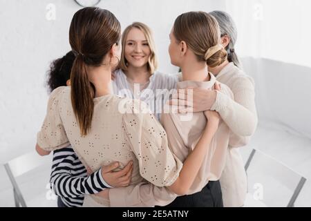 Glückliche Frauen umarmen sich während des Seminars im Tagungsraum Stockfoto