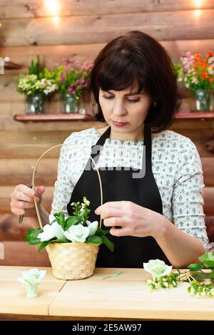 Der Shop-Mitarbeiter sammelt Blumenstrauß und Seife in einem Korb. Stockfoto