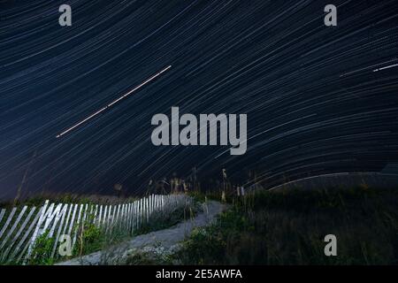 Eine lange Belichtung zeigt den Weg der Sterne am Himmel über Atlantic Beach, North Carolina. Stockfoto