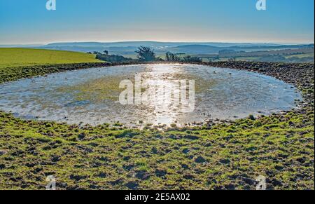 Wintersonne reflektiert auf Ditchling Beacon Teich, der den Tau spaltet Teich in zwei Stockfoto