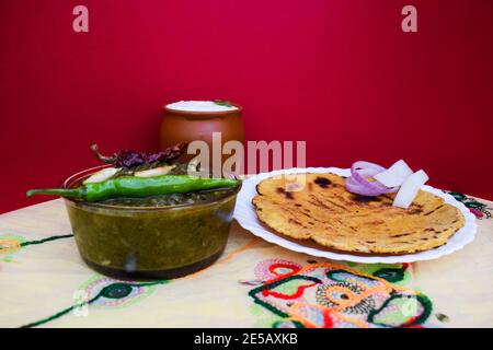 Seitenansicht von Makki di roti und Sarson da saag, Senfblätter Curry und ungesäuertes Maismehlbrot auf authentische Weise mit Zwiebeln und Grün serviert Stockfoto