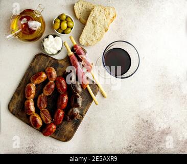 Spanische Bratwürste auf dem Schneidebrett - butifarra blanca, Chorizo, morcilla de cebolla, Jamon und Knoblauch aus aioli Stockfoto