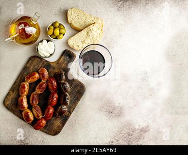 Spanische Bratwürste auf dem Schneidebrett - butifarra blanca, Chorizo, morcilla de cebolla, Jamon und Knoblauch aus aioli Stockfoto