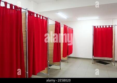 Leere Umkleidezimmer mit roten Vorhängen und weißen Wänden. Umkleidekabinen im Bekleidungsgeschäft ohne Personen Stockfoto