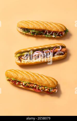 Gourmet Dirty Hot Dog Sandwich mit verschiedenen Garnierung auf gelbem Hintergrund. Gesunde Fast-Food-Option. Stockfoto